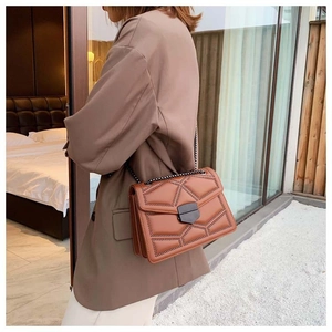 Side view of caramel brown crossbody bag with geometric stitching and metal chain strap