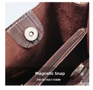 Detail view of deep brown crocodile texture bag with magnetic clasp and zipper pocket