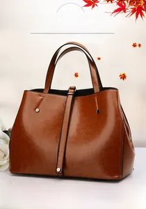Détail de la texture d'un sac cabas en cuir marron vintage avec boucles métalliques chic