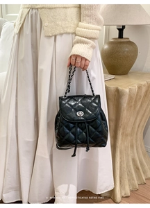 Close-up of black quilted mini backpack featuring silver turn-lock and chain straps