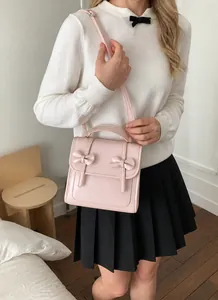 Dettaglio della borsa in pelle rosa con doppi fiocchi e tracolla regolabile