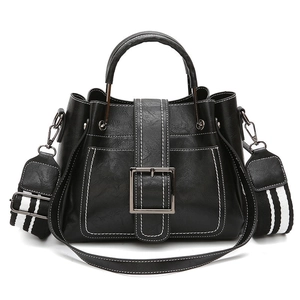 Detail of black PU bucket bag with white contrast stitching and wide striped strap