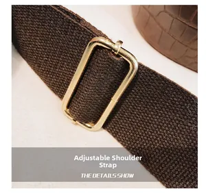Detailed macro view of adjustable woven canvas shoulder strap with gold metal buckle