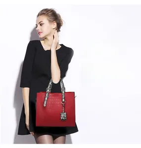 Detail of red crocodile texture handbag with snake print handles on female model