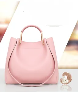 Detailed view of pink faux leather handbag with circular metal handles and crossbody strap