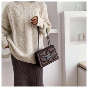 Detail of brown quilted leather bag with chain strap and vintage metal clasp
