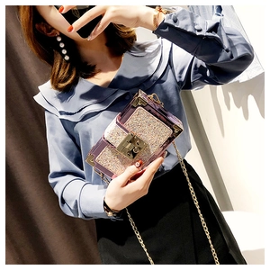 Detail of sequin clutch bag with gold hardware and chain strap on female model