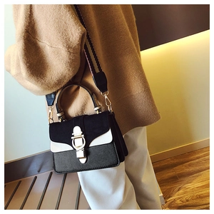 Detail of color-block bag with golden horseshoe lock and wide striped textile strap