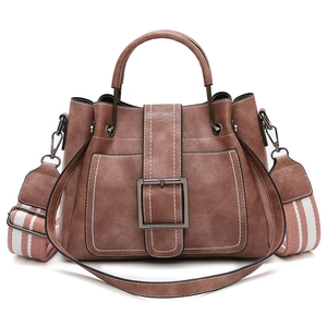 Detail of caramel brown retro bucket bag with metal buckle and striped woven strap
