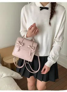 Detalle de mochila rosa claro con lazos decorativos y cierre metálico de moda