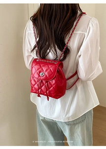 Macro shot of red quilted patent leather mini backpack with silver twist lock and chain strap