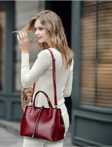 Detail of dark red crocodile grain leather tote with polished round handles and strap