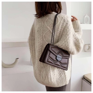 Detail of dark brown leather crossbody bag with rivet geometric stitching and chain strap