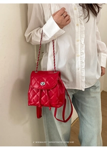 Detail of red quilted backpack showing silver twist lock and woven chain straps