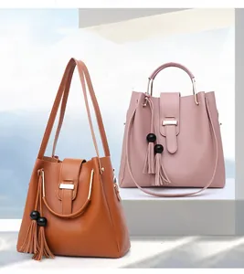 Detail of elegant leather tote bag with tassel charm and polished metal handle rings