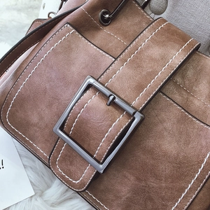 Detail of vintage brown leather bucket bag showing white contrast stitching and metal buckle