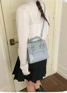 Mochila azul claro con lazos combinada con jersey blanco y falda de tablas negra