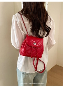 Detail of red quilted mini backpack with silver turn-lock and chain strap for women