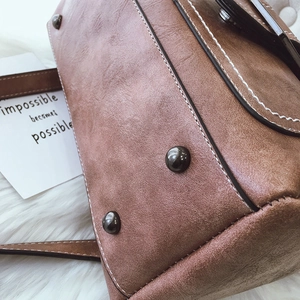 Detail of brown vintage bucket bag showing contrast stitching and metal bottom studs