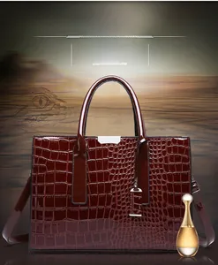 Macro detail of wine red faux crocodile skin texture and silver hardware on tote bag