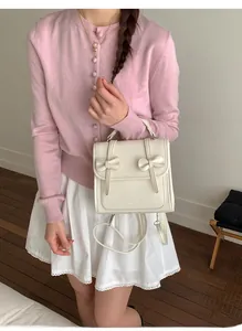 Detalle de mochila crema con lazo mostrando textura de cuero vegano y correas ajustables