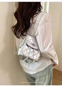 Detail of silver quilted backpack with metal chain straps and drawstring closure