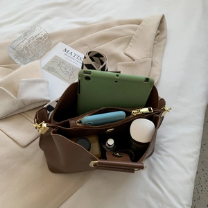 Brown leather bucket bag with geometric strap and high capacity for essentials