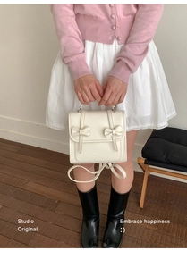 Detalle de mochila de cuero blanco crema con lazos decorativos y cierre de solapa
