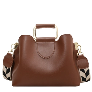 Brown leather bucket bag with gold metal handle and woven geometric shoulder strap