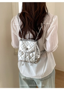 Detail of mini silver quilted backpack with metallic chain strap and twist lock
