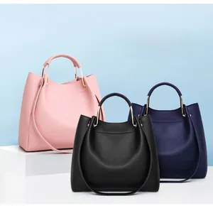 Three minimalist leather tote bags in pink, black and blue with gold metal handles