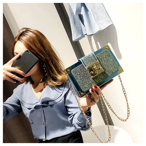 Close-up of glittery teal crossbody box bag with gold metal corners and chain strap