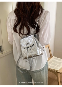 Detail of silver metallic quilted mini backpack with chain strap and twist lock
