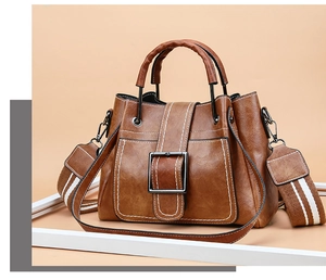 Detail of vintage brown bucket bag with white contrast stitching and wide stripe strap