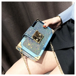Detail of blue sequin box bag with gold metal corners and clasp closure on a chain