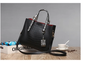 Detail of black crocodile texture tote with snakeskin handles and red lining