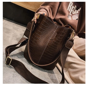 Detail of brown crocodile pattern bucket bag with wide strap and gold hardware