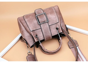 Detail of a dusty pink vintage bucket bag with contrast stitching and metal buckle