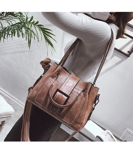 Detail of retro bucket bag with contrasting white stitching and striped wide strap