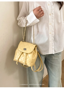 Detail of light yellow quilted mini backpack with silver twist lock and chain strap