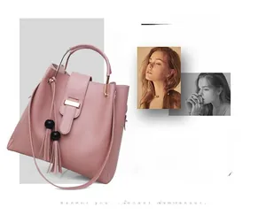 Close-up of pink leather handbag featuring a metal circular handle and decorative tassel