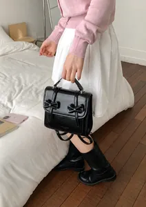 Dettaglio borsa in pelle nera con fiocchi simmetrici e logo in rilievo di classe