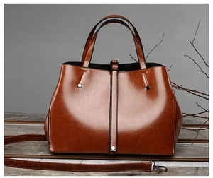 Détail d'un cabas en cuir marron poli avec poignées et bandoulière amovible pour femme