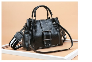 Detail view of black faux leather bucket bag with white contrast stitching and silver hardware