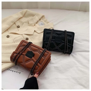 Detail view of brown and black quilted crossbody bags with rivets and metal chain straps