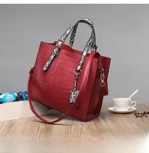 Detail of red crocodile texture tote with snakeskin handles and gold-tone pendant charm