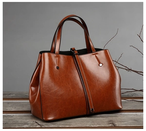 Detail of caramel brown PU leather tote showing glossy texture and metallic buckle accents