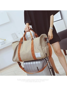 Détail du sac de voyage kaki avec sangles brunes posé sur une valise argentée