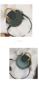 Detailed view of dark green round bag with gold metal handle and rivet accents