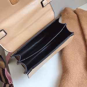 Sac bandoulière bicolore avec compartiment accordéon et sangle rayée vue de profil en gros plan
